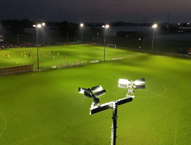 Luchtbeeld van een verlicht sportterrein bij avond