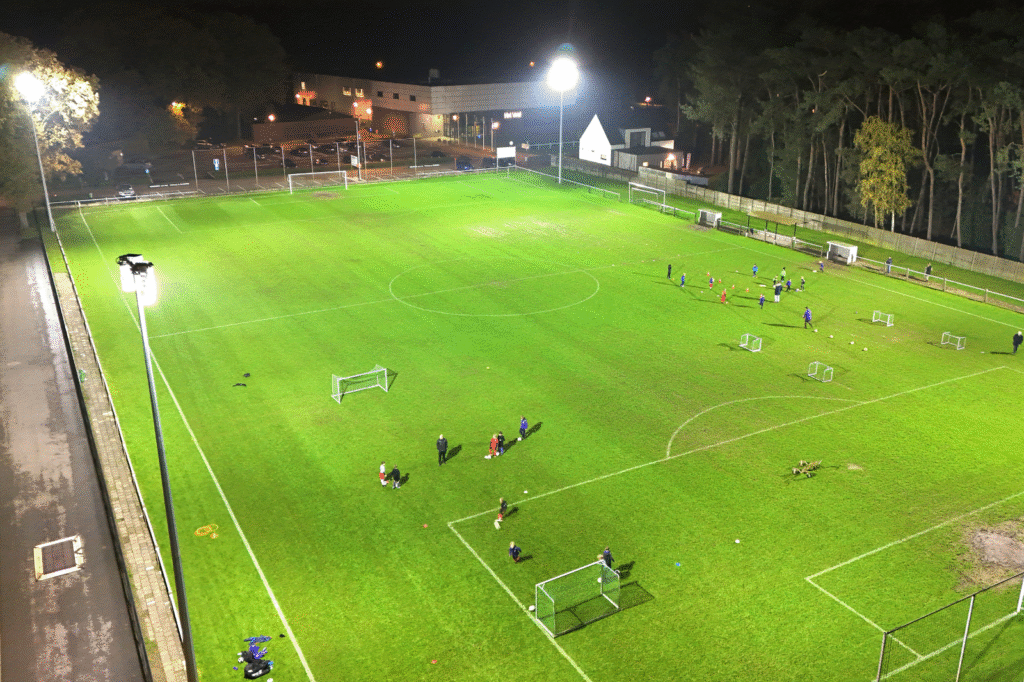 Soccer field lit with smart LED sports lighting during an evening training session, with uniform light across the entire field