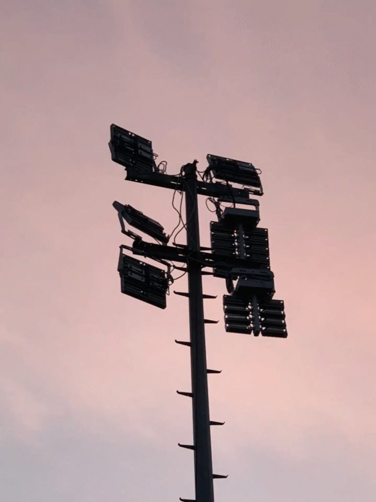 LED-armaturen gemonteerd op een hoge mast voor efficiënte verlichting van een atletiekpiste.