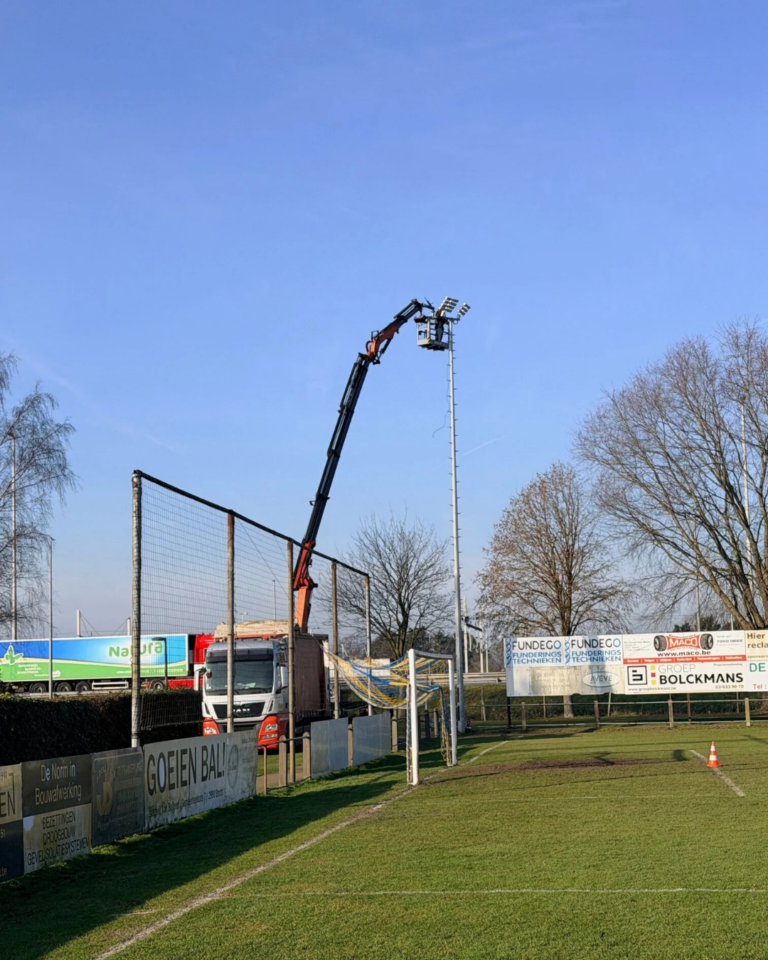 Plaatsing van een nieuwe LED-verlichtingsmast op het terrein van K. Brecht SK door het Ecosports-installatieteam.