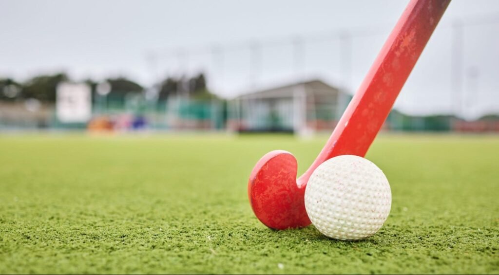 Hockeybal en stick op kunstgras onder ledverlichting hockeyveld met scherp zicht