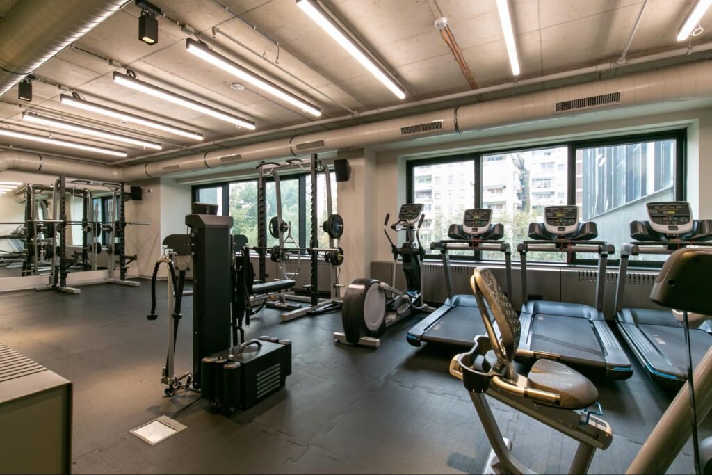 Moderne fitnessruimte met helder, gelijkmatig LED-plafondlicht boven cardio- en krachttoestellen